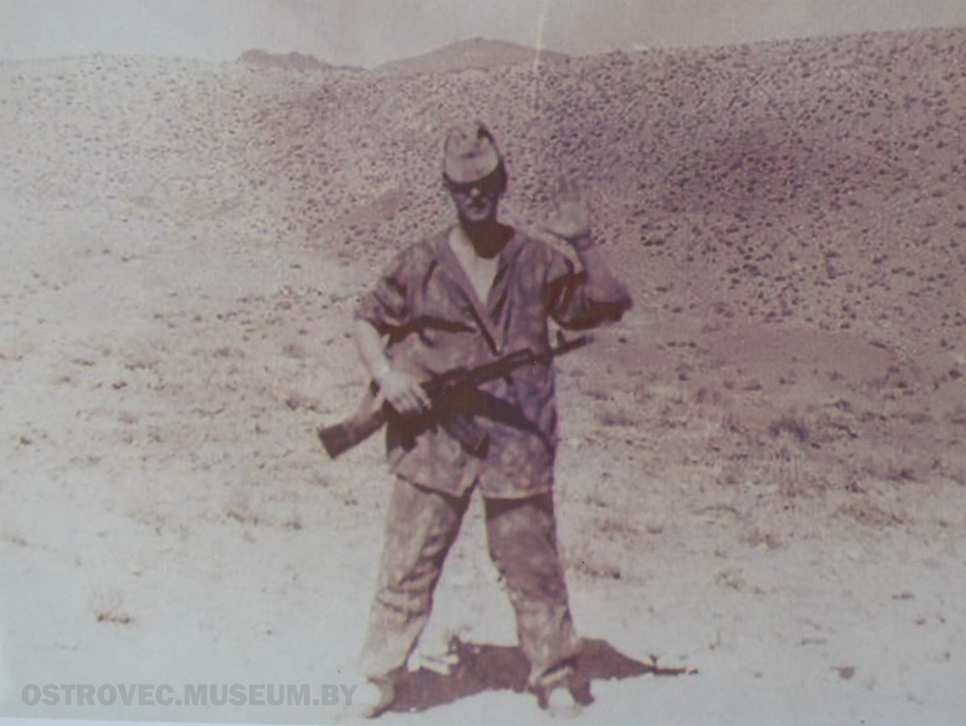 Лисовский Геннадий Иванович с автоматом через плечо посреди полупустынного отрога. Афганистан, 1983 г. 